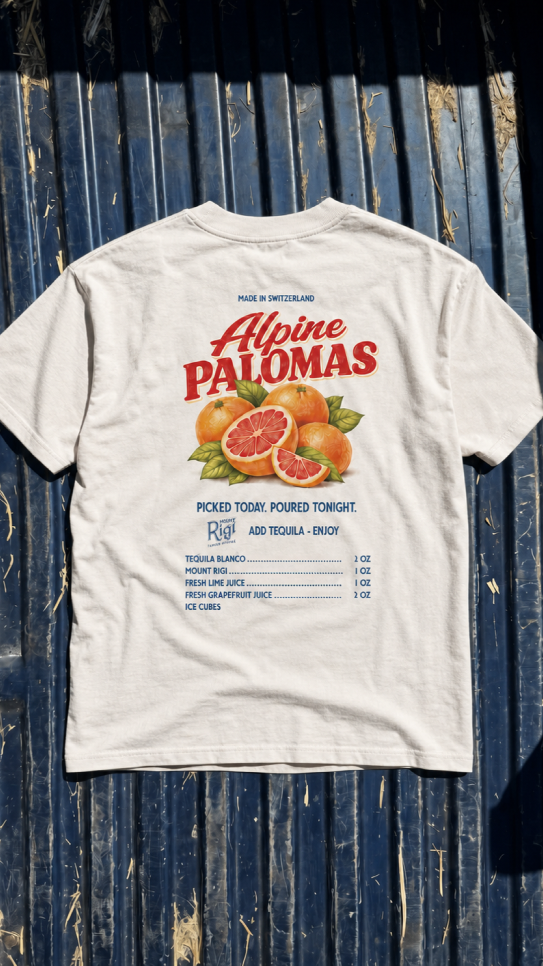 Sunlit flatlay of the white Mount Rigi Alpine Palomas T-shirt featuring grapefruit artwork and a cocktail recipe